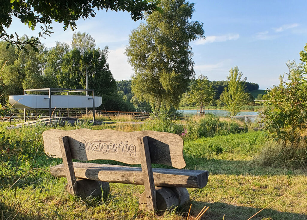 Über uns Holzbank mit Schriftzug «Einzigartig» auf der Rückenlehne, Nahe beim Moossee